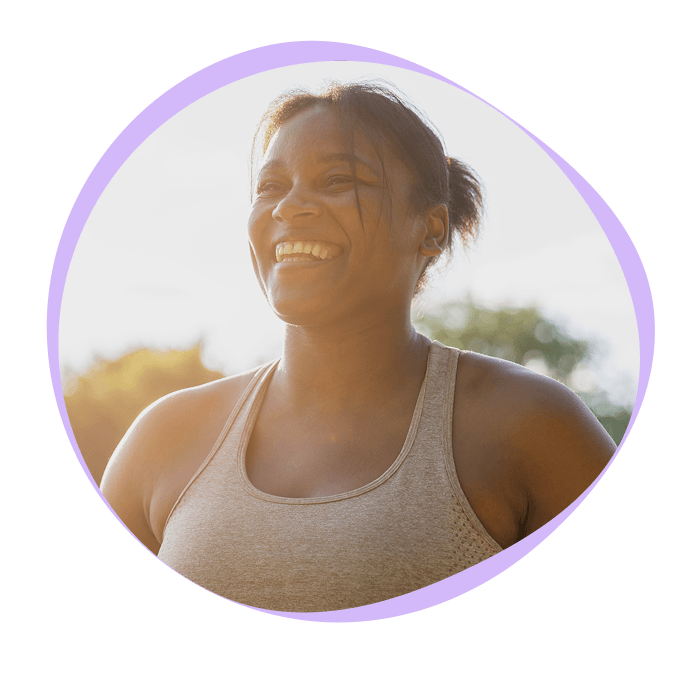 A woman in athletic wear smiles outdoors, with sunlight behind her, framed by a purple circular border.